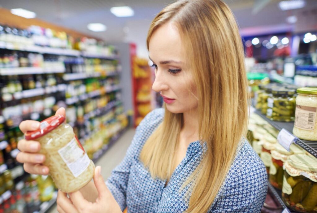 Donna che consulta l'etichetta nutrizionale di un prodotto alimentare al supermercato