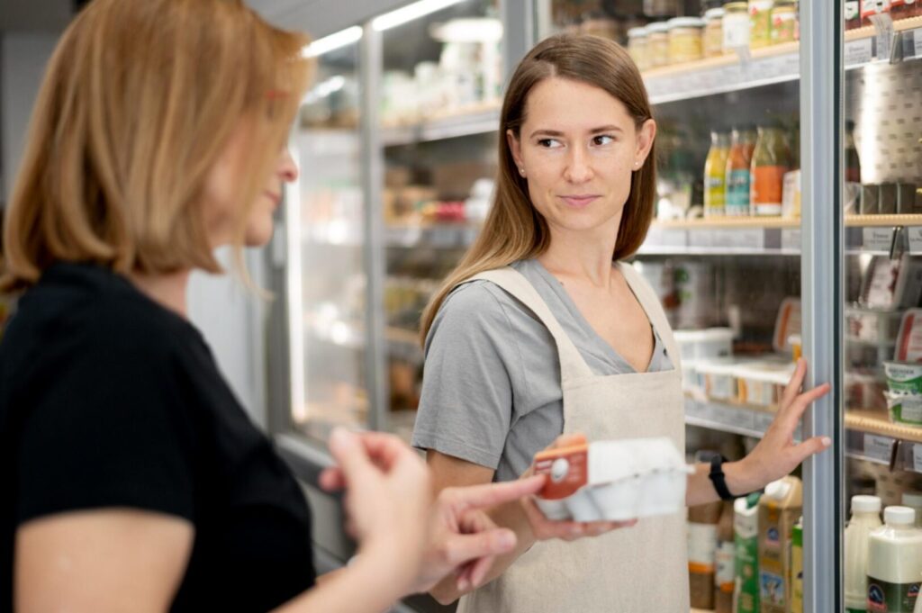 Operatore del settore alimentare mostra etichetta di un prodotto al cliente in negozio per corretta informazione del consumatore.